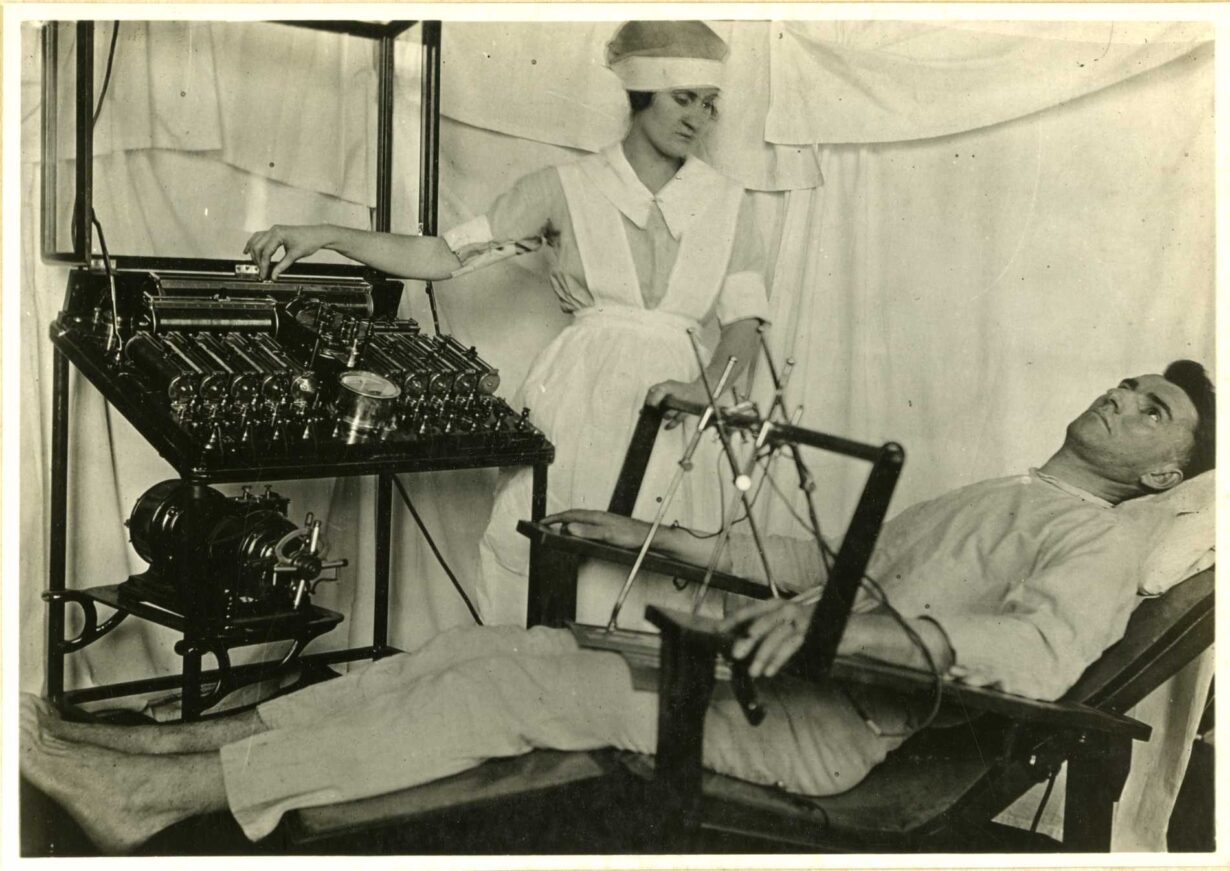 A nurse using medical equipment. To her left is a man laying in a chair and looking upward.