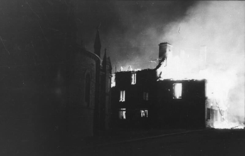 Image en noir et blanc d'un bâtiment en feu. Le toit s'est complètement effondré.