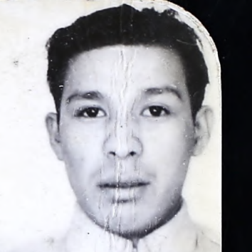 A black and white image of a man from the shoulders up. he is facing the camera and is wearing a military uniform. The photograph is slightly damaged.