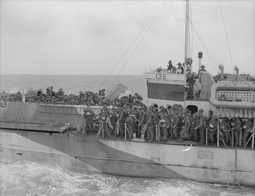 Image en noir et blanc d'un navire en mer. Le pont du navire est rempli de soldats.