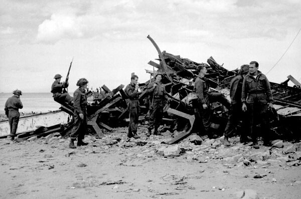 un groupe de soldats autour de pièces d'équipement militaire cassées sur une plage.