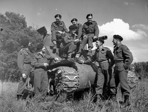 Un groupe de soldats autour d'un char.Quatre soldats se tiennent de chaque côté du char, tandis que quatre autres sont assis dessus.