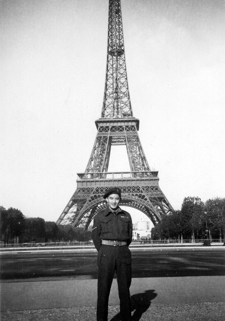 Image d'un soldat souriant. Il se tient devant la Tour Eiffel.