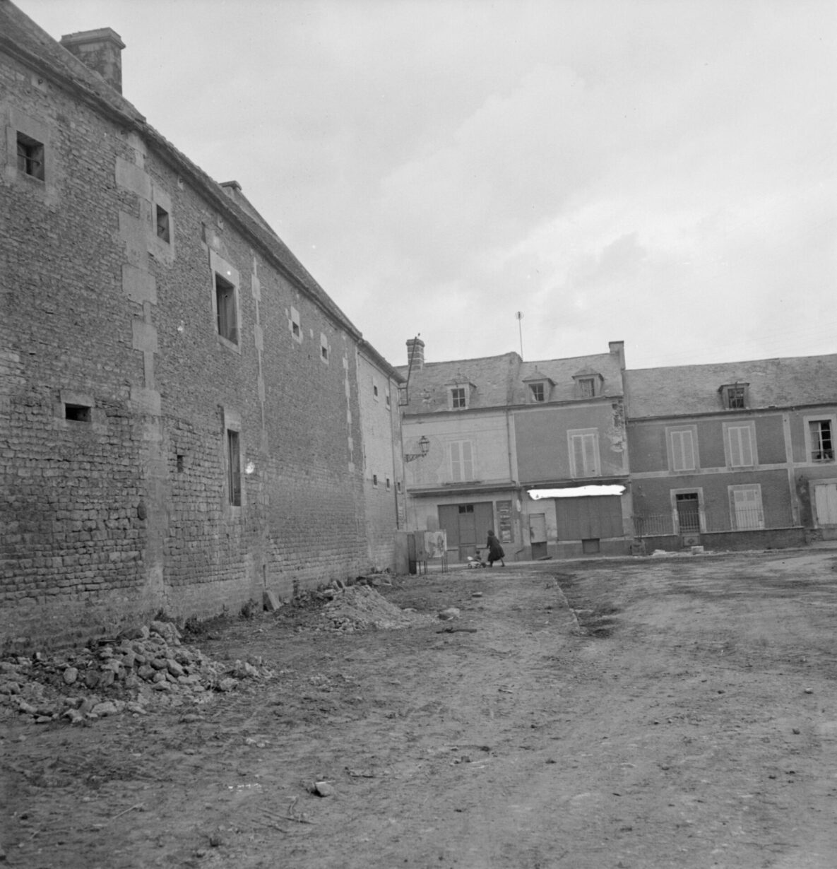 Une cour. Au loin, une femme et un enfant.