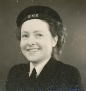 Portrait en noir et blanc d'une femme souriante. Elle porte un uniforme militaire.