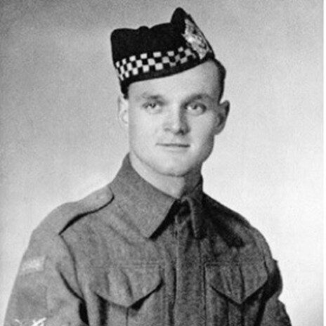 Photo en noir et blanc d'un homme en uniforme militaire.Il porte un chapeau Glengarry et est assis.