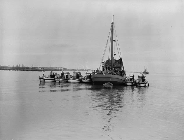 Image d'un grand navire déplaçant six navires plus petits dans l'eau.