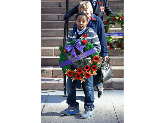 Un élève du Toronto Catholic District School Board (TCDSB) déposant une couronne de fleurs lors du jour du Souvenir