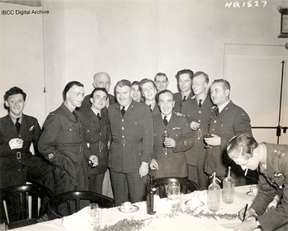 Un groupe d'aviateurs en uniforme debout derrière une table. Beaucoup ont des brûlures. Ils sourient.
