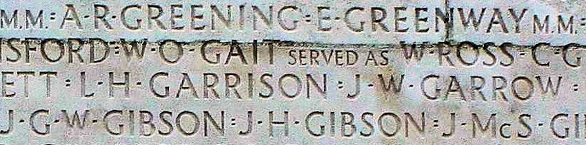 Une partie d'un mur de pierre. Il y a un texte gravé dessus, comprenant les mots « J G W Gibson ».