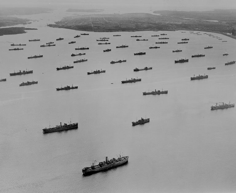 A group of ships in a body of water near land.