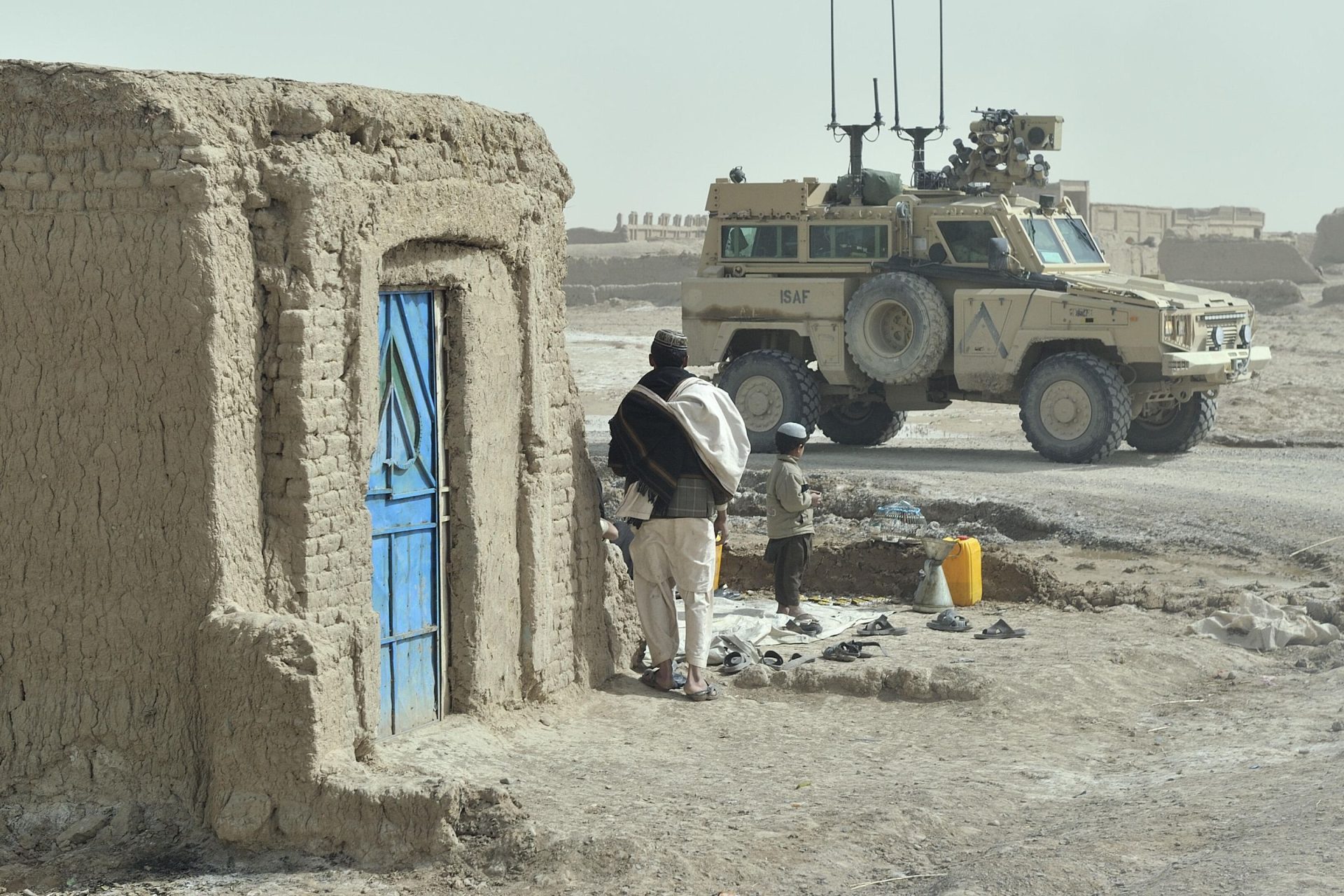 A man and a boy looking at a military vehicle in Afghanistan.