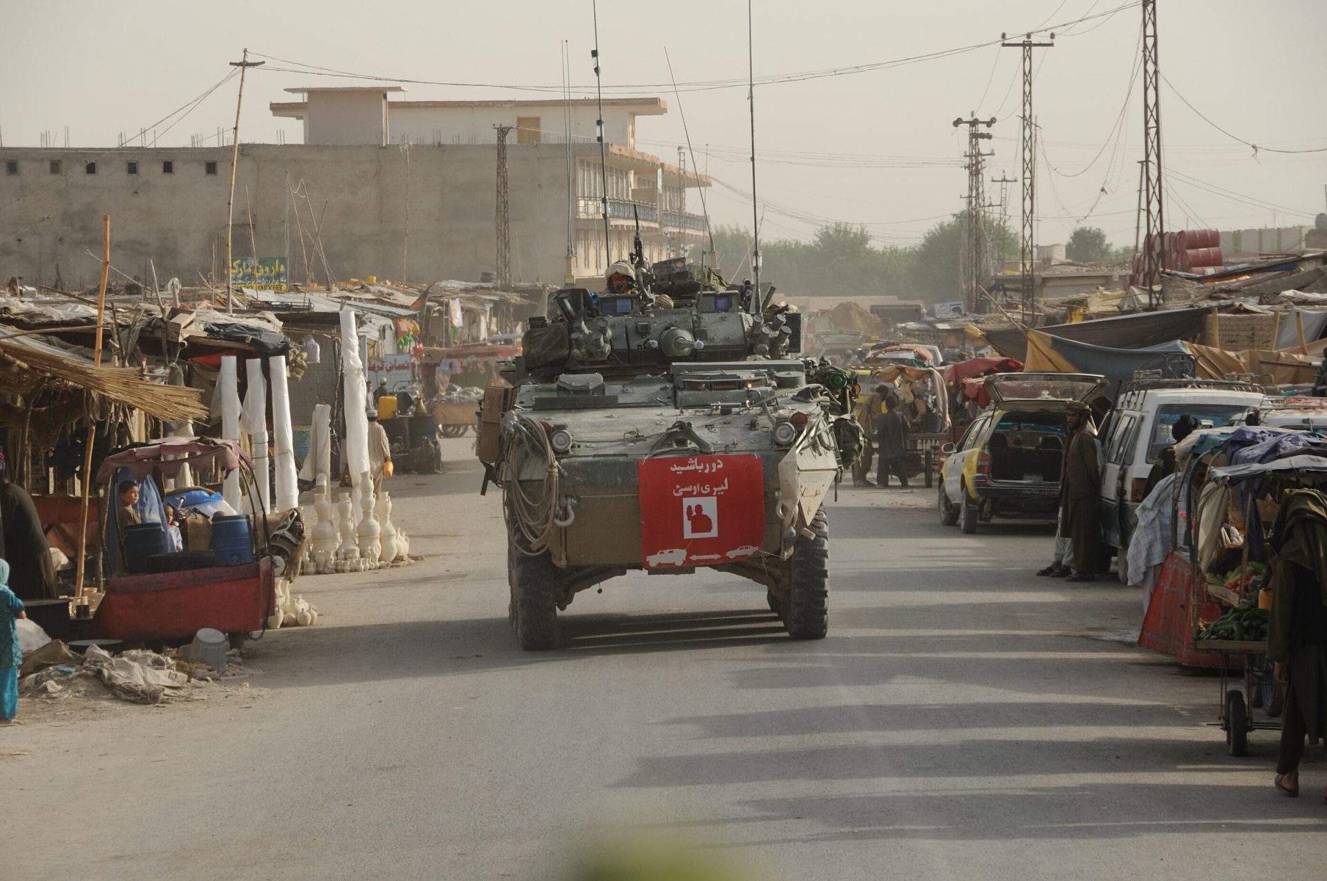 A light armoured vehicle driving in a crowded street.