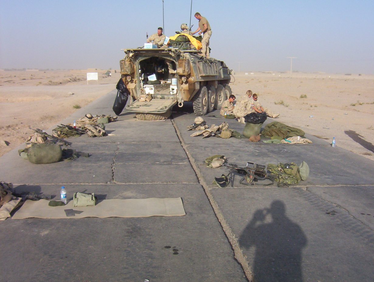 un groupe de soldats se reposant près d'un véhicule blindé léger.