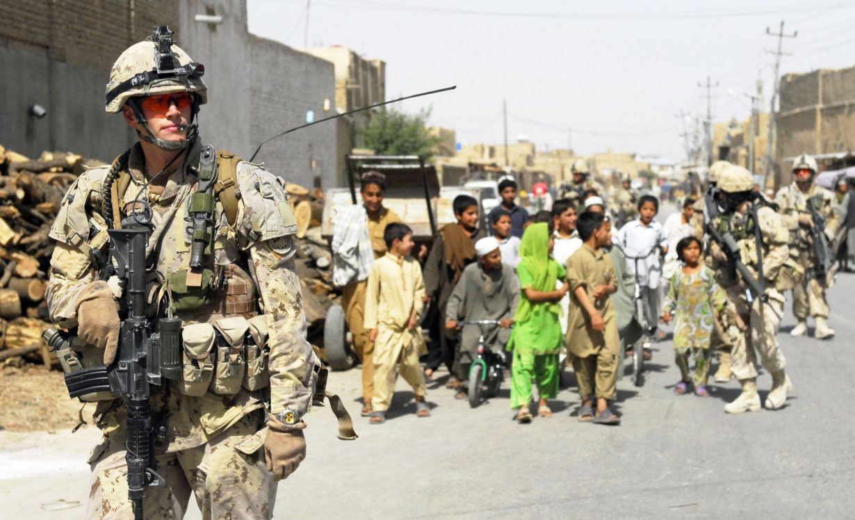 des soldats et des Afghans marchant ensemble dans une rue.