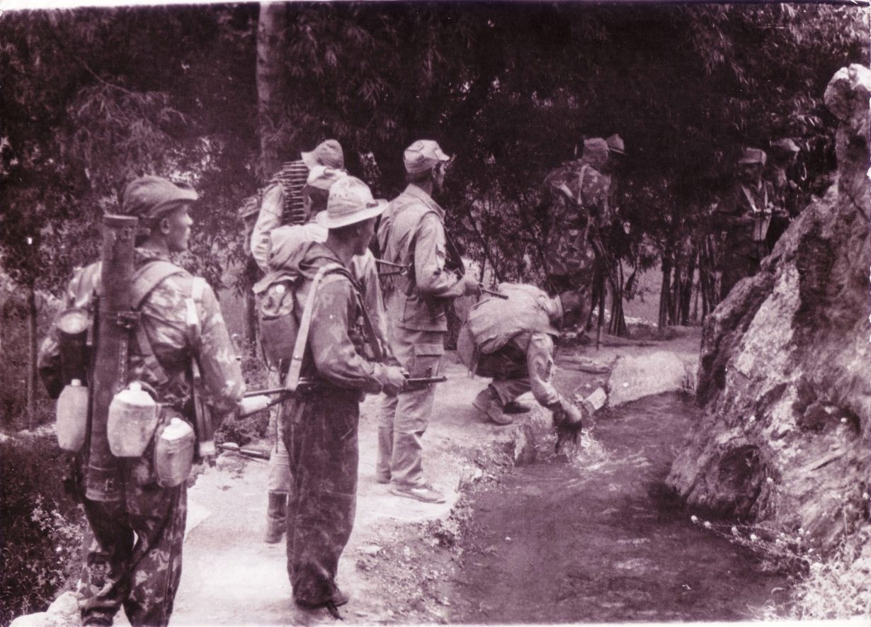 Un groupe de soldats debout près d'un ruisseau dans une zone boisée.
