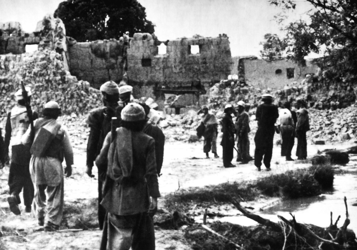 Un groupe d'hommes regardant les ruines d'un bâtiment.