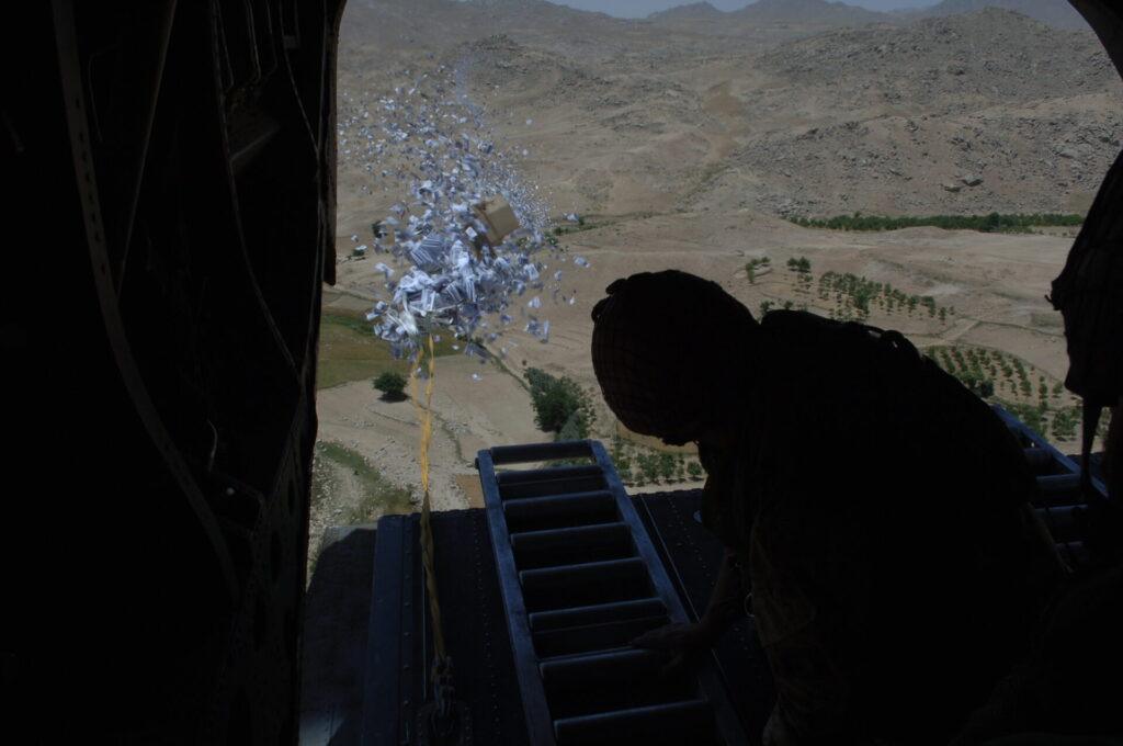 Un soldat larguant des tracts depuis un avion militaire.