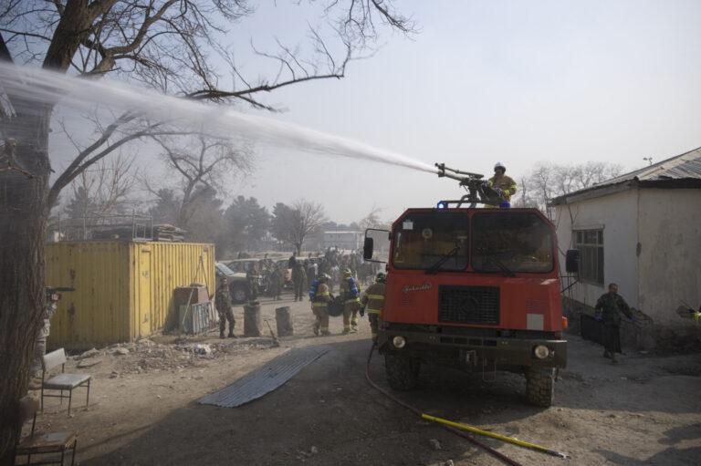 Un pompier perché sur le toit d'un camion de pompiers arrosant la foule avec un canon à eau.