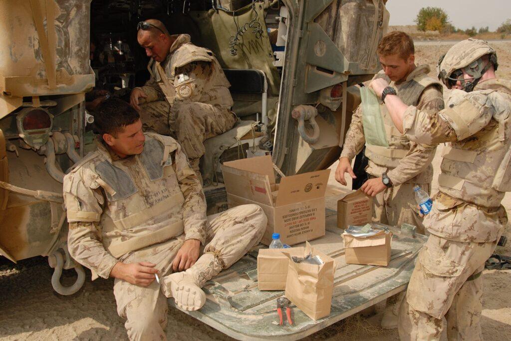 Un groupe de soldats prépare à manger près d'un véhicule blindé.