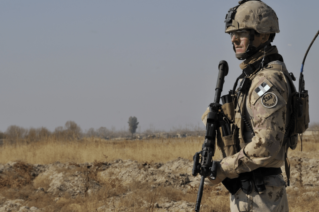 Un soldat dans un champ. Ils portent un badge sur lequel est inscrit «&nbsp;ISAF&nbsp;».