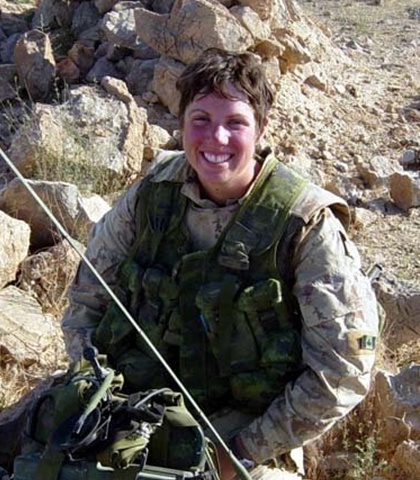un soldat en uniforme. Elle est assise sur des rochers.