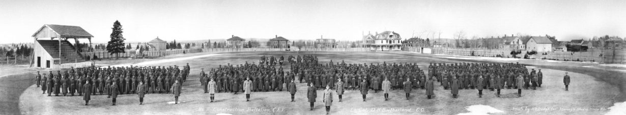 Une photographie en noir et blanc d'un groupe de soldats. Ils sont au garde-à-vous dans un champ.