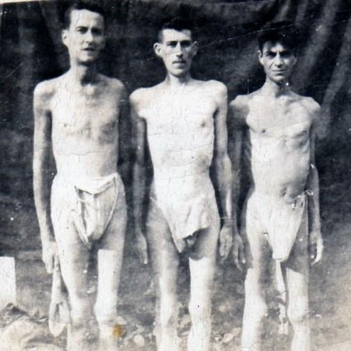 Un groupe de trois hommes émaciés vêtus de pagnes.