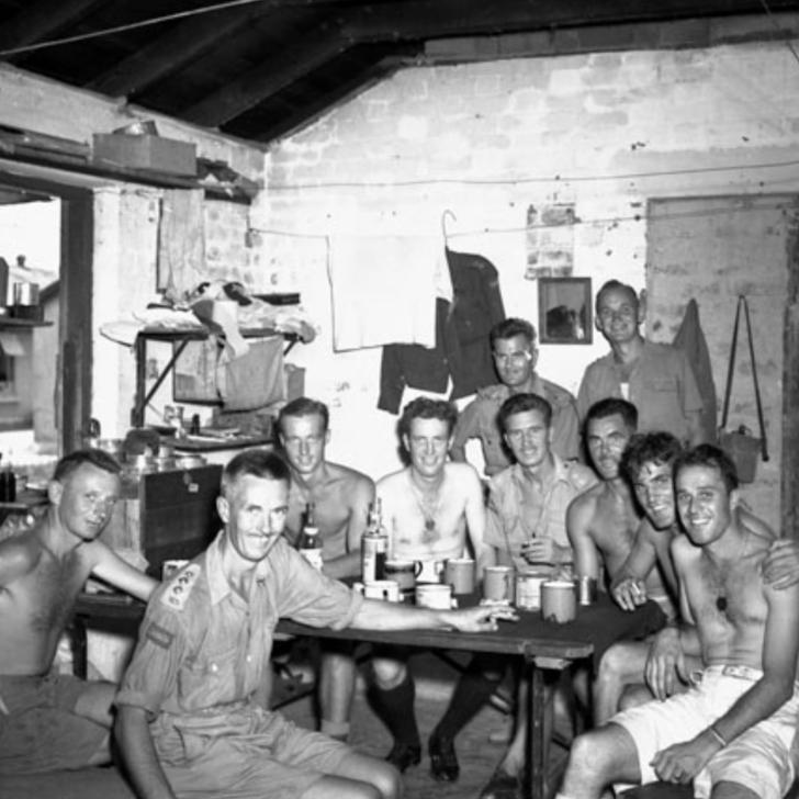 Un groupe d'hommes assis autour d'une table. Ils sourient.