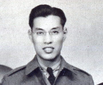 Un homme en uniforme qui porte des lunettes. Il sourit.