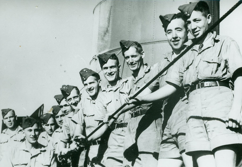 A group of soldiers on a ship. They are facing the camera and smiling.