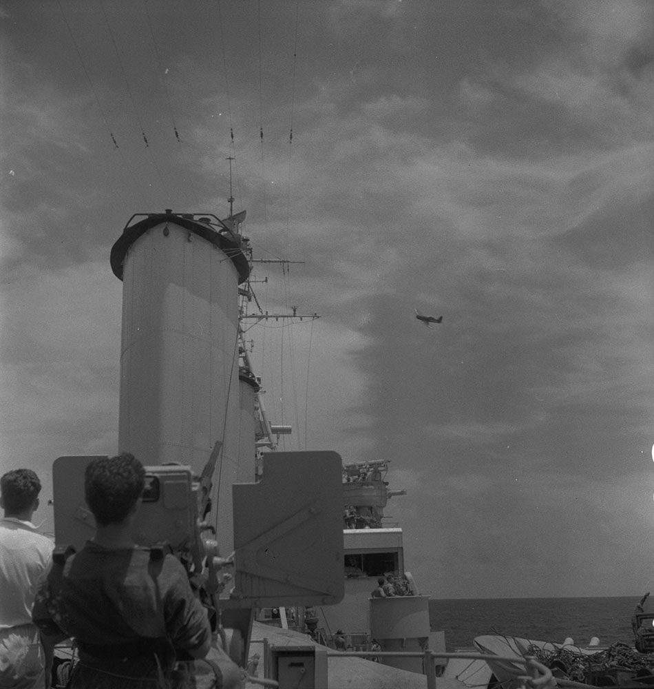 Un avion survolant un navire militaire.