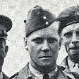 Un homme en uniforme debout aux côtés de deux autres hommes.