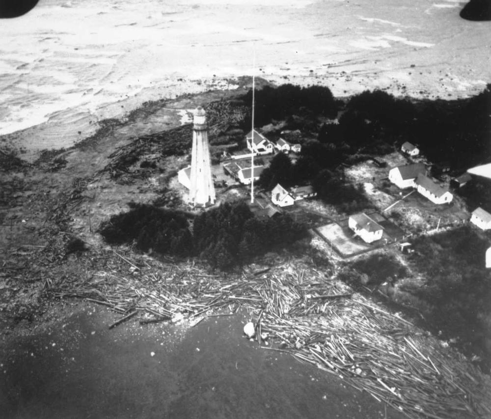 Une photographie aérienne montrant plusieurs bâtiments, dont un phare, au bord de la mer.