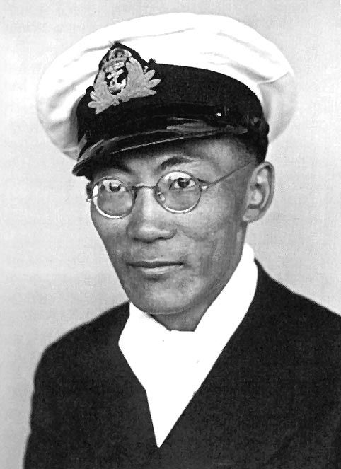 Un homme en uniforme de la marine. Il porte des lunettes rondes.