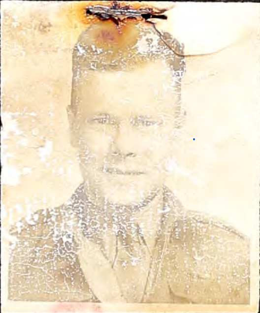 Une photographie sépia représentant un homme. L'image est très défraîchie et présente quelques traces d'usure dans la partie supérieure, là où elle a été agrafée à un support.